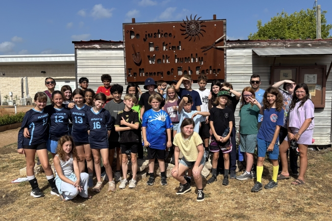 a large group of children and their teachers in front of the tool shed